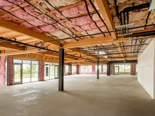 Plateau brut en rénovation avec isolation apparente, structure bois, réseaux techniques visibles et grand espace ouvert avant aménagement intérieur.