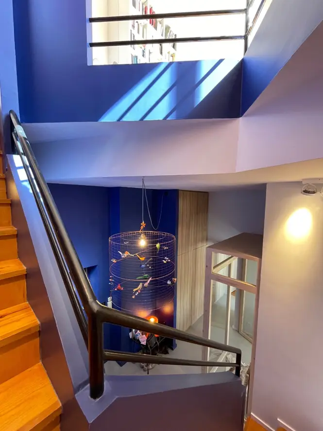 Escalier intérieur design avec garde-corps noir, murs bleu intense et espace en double hauteur dans une rénovation contemporaine.
