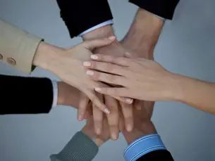 Mains empilées en équipe symbolisant collaboration et travail collectif, projet professionnel ou chantier en architecture intérieure.