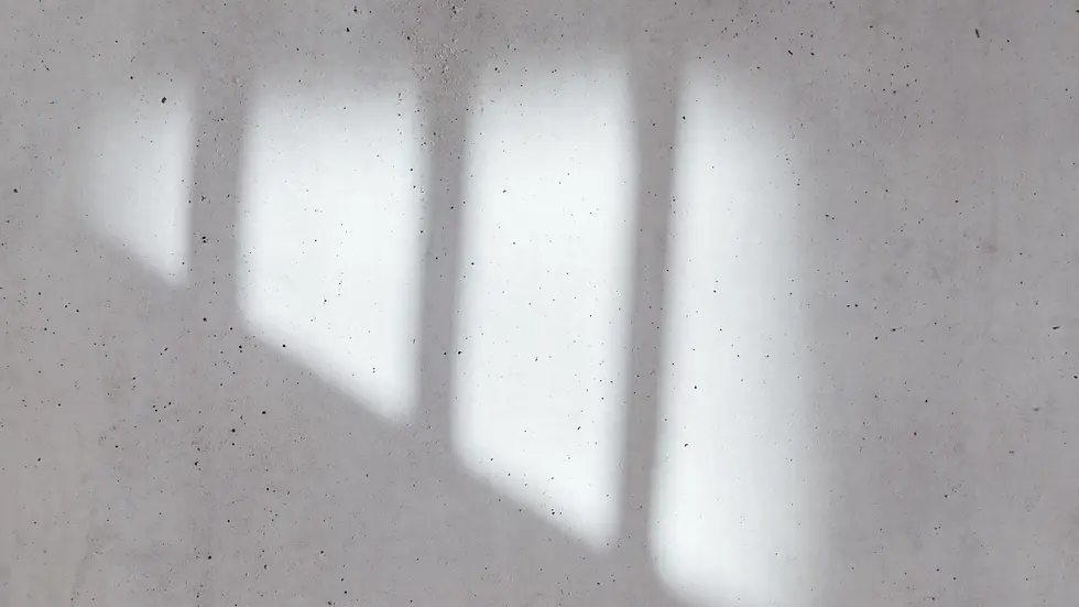 Ombres de fenêtres projetées sur mur en béton, jeu de lumière naturelle et ambiance minimaliste architecturale.