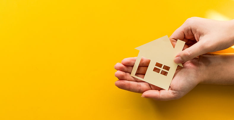 Hands holding paper house cutout representing real estate support and help
