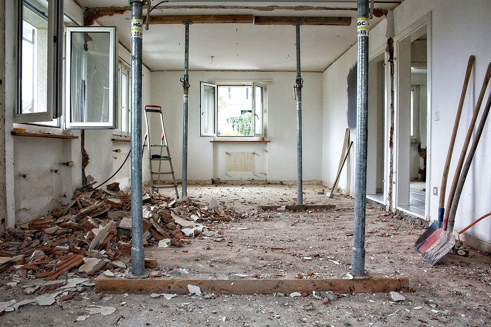 Room under renovation with debris on the floor, open windows, support beams, and tools.