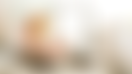 Woman hand-washing dishes in a bright kitchen sink, using natural cleaning methods with a fruit bowl in the background.