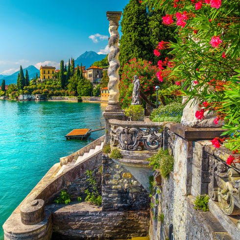 Picturesque landscape with lake and mediterranean buildings. Fresh oleander flowers and be