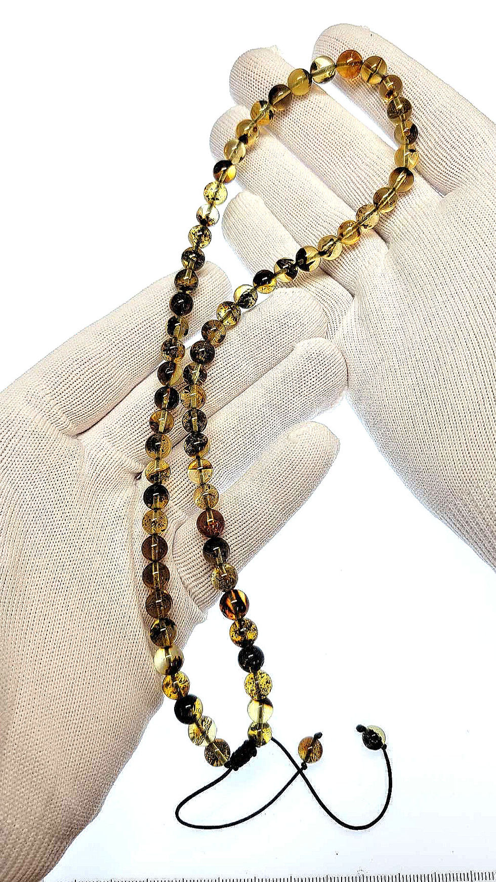 Thumbnail: Dominican amber round bead necklace held by two hands