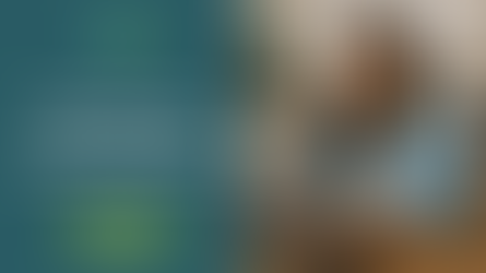 Woman smiling at laptop in cozy kitchen with white cabinets, round mirror, and potted plant. Warm, inviting atmosphere.