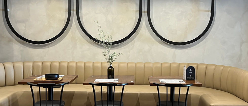 Mustache Restaurant : Foto einer gebogenen Sitzbank mit Holztischen, schwarzen Metallstühlen und dekorativen Wandschleifen.