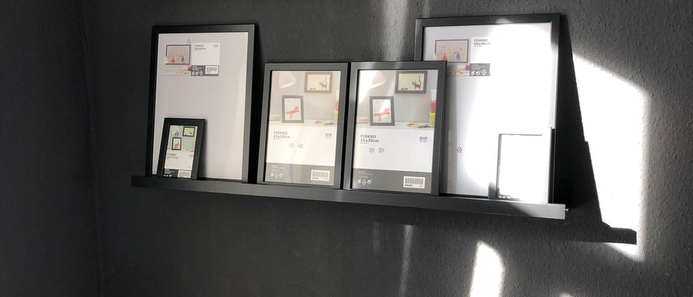 Wohnung Berlin Mitte: Detail einer Sitznische mit gemusterten und rosafarbenen Kissen sowie Bilderleisten an einer anthrazitfarbenen Wand.