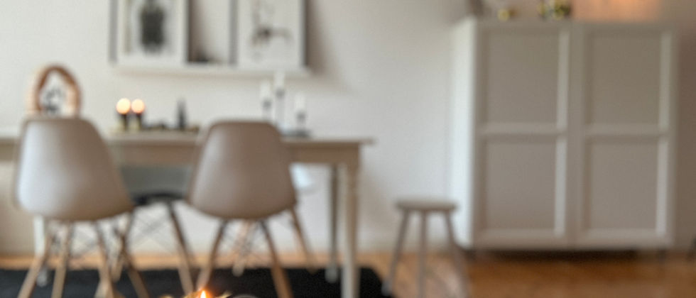 Wohnung Berlin Mitte: Wohnraumfoto mit Kerzendekoration auf Couchtischen im Vordergrund und weißem Essplatz im Hintergrund.
