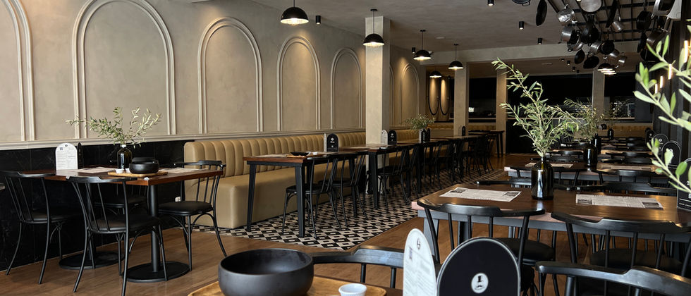 Mustache Restaurant : Foto der Tischreihen entlang der Polsterbank unter schwarzen Pendelleuchten und aufgehängten Pfannen.