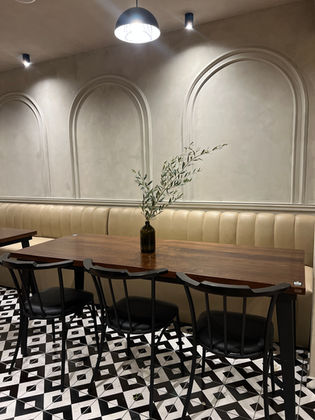 Restaurantdesign – Mustache Restaurant: Seitlich aufgenommenes Foto von Sitzbank, Holztisch und geometrischem Bodenmuster. | EN: Mustache Restaurant photograph: side view of a banquette, timber table and geometric flooring.