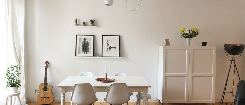 Wohnung Berlin Mitte: Foto eines weißen Esstischs mit hellen Stühlen, Pendelleuchten, weißem Sideboard und Gitarre auf einem Holzdielenboden.