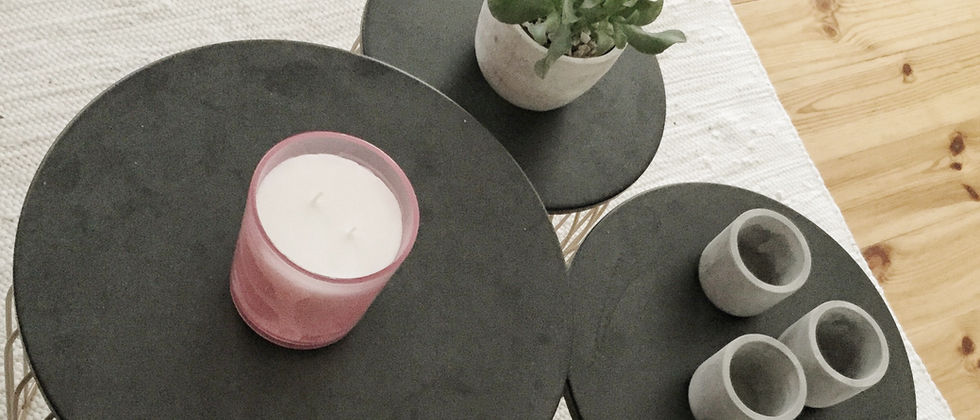Wohnung Berlin Mitte: Detail von drei runden schwarzen Tischen mit filigranen Gestellen, Pflanze, Tassen und Kerze auf hellem Teppich.