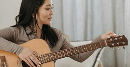 תקריב של אישה מחזיקה גיטרה ומכוונת אותה