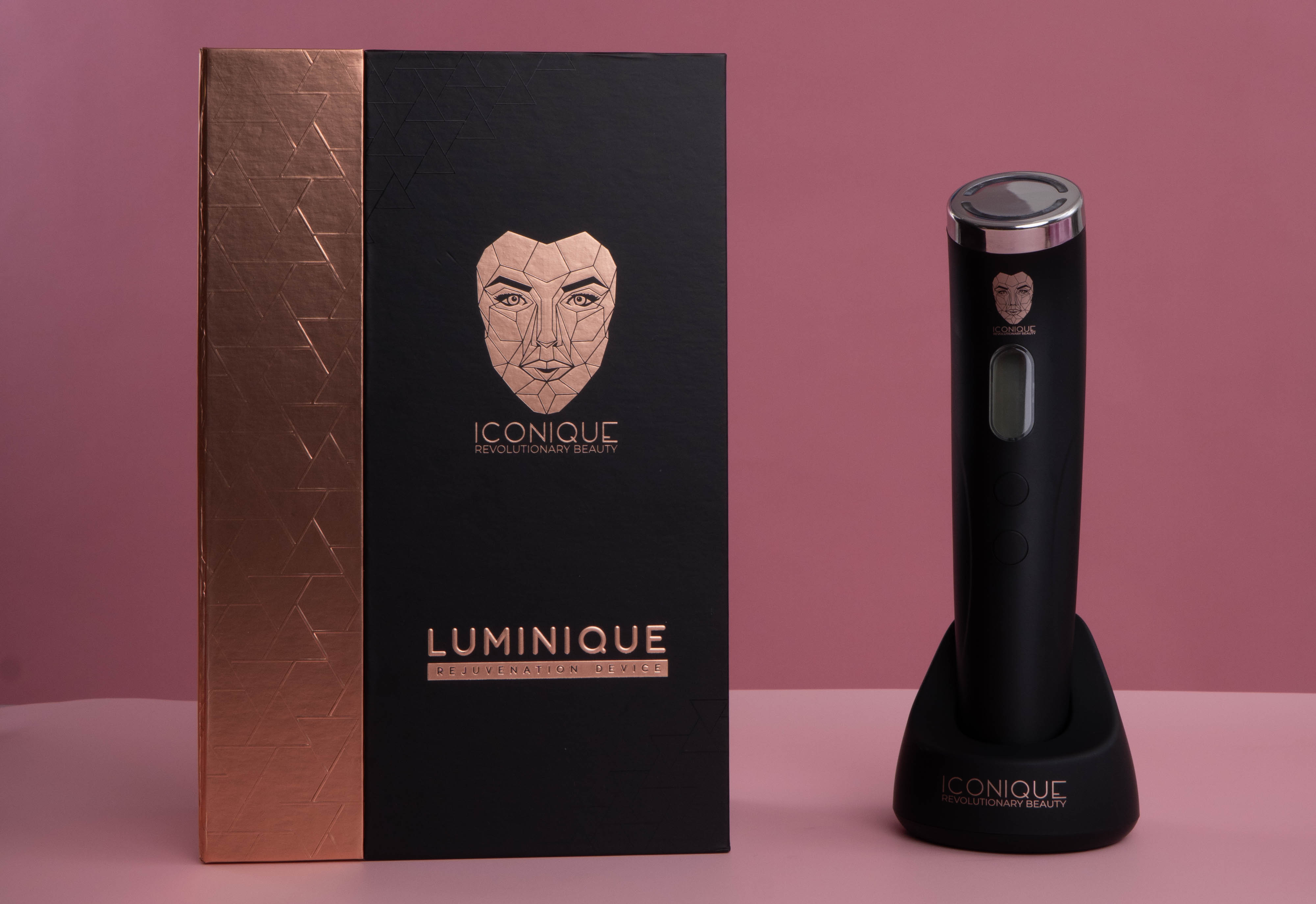 ICONIQUE Luminique rejuvenation device with its black and rose gold packaging displayed beside the handheld device on a soft pink background.