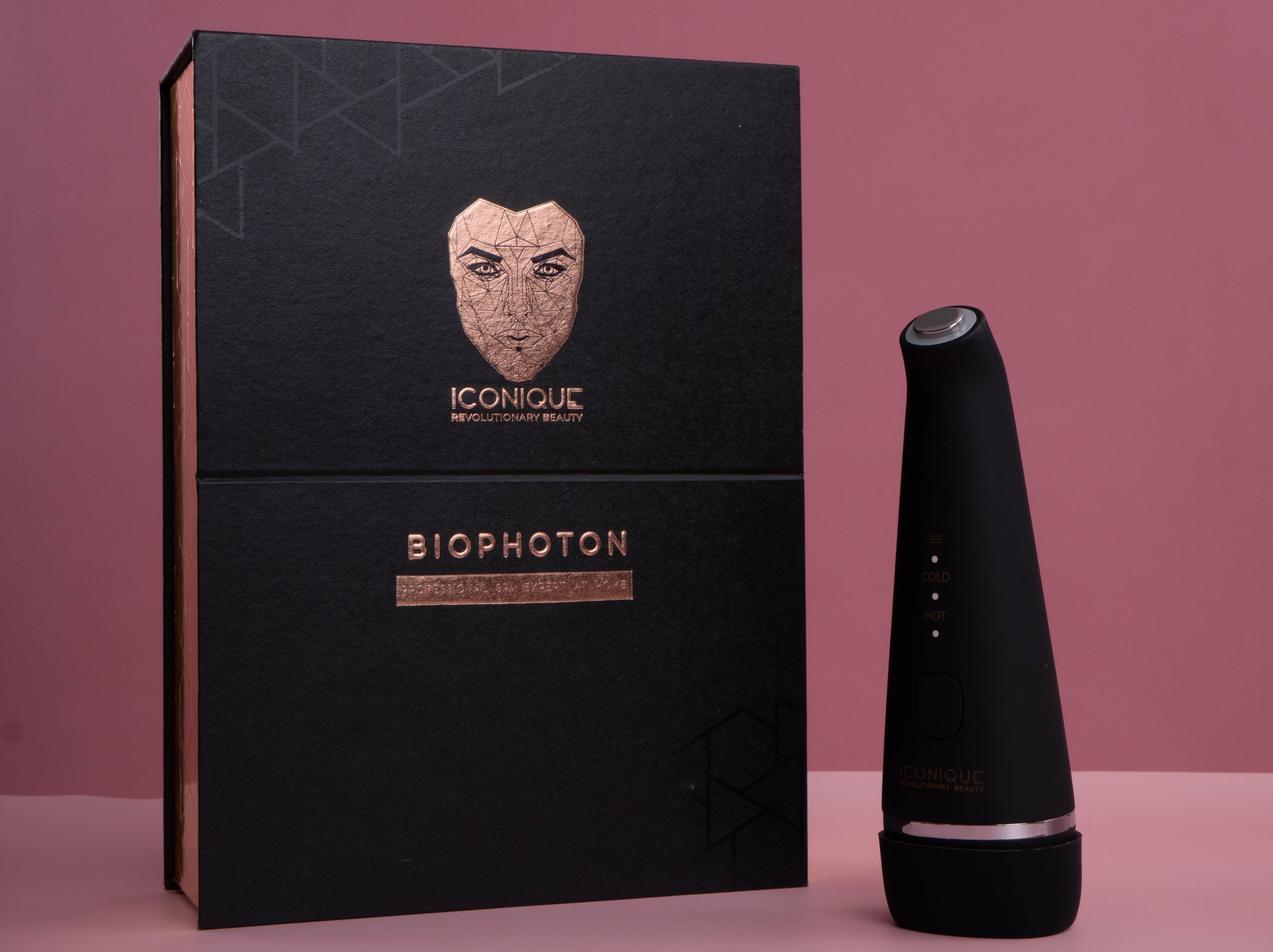 ICONIQUE Biophoton skincare device displayed beside its black branded box on a soft pink background.