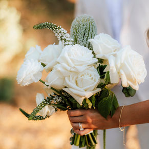 Close-up of a bride holding a white wedding bouquet with ranunculus and greenery during a Yosemite outdoor wedding.