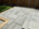 Newly laid light grey patio slabs spread across a garden area