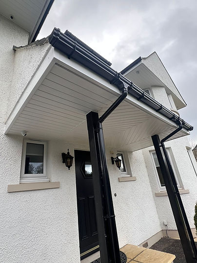 White house entrance with newly installed black gutters and white fascia.