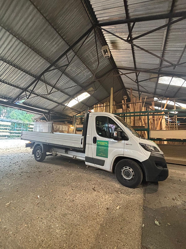 A white flatbed truck is parked inside a spacious lumber warehouse