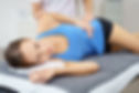 Young Woman Lying on her Side on bed While the Physical Therapist is giving a Treatment to