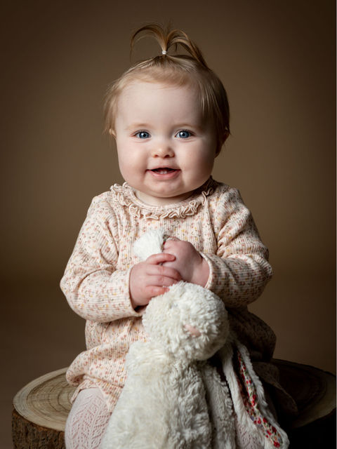 Baby fotografering af pige på 1 år siddende på træstub