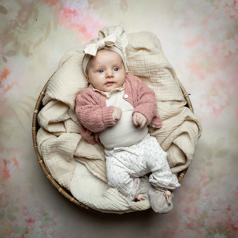 Babyfotografering af nyfødt liggende i kurv med blomstret baggrund
