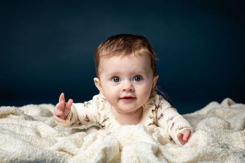 Babyfotografering af pige liggende på tæppe med blå baggrund