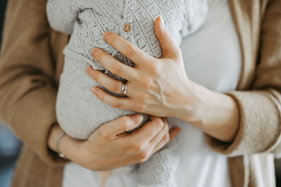Eine weibliche Hand drückt ein neugeborenes Baby an sich