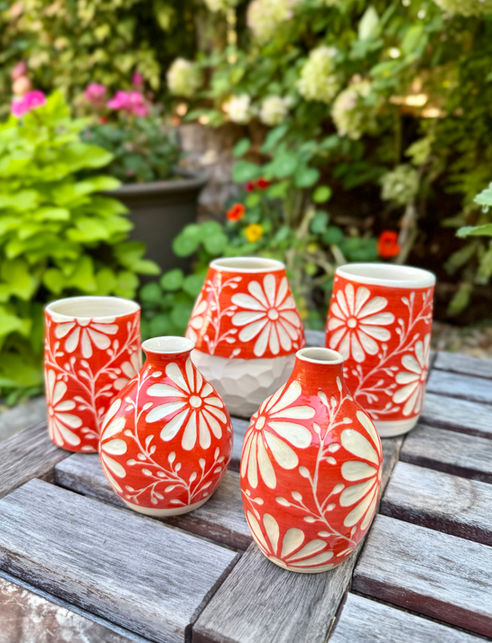 set of 5 handmade ceramic vases that are bright orange, made on a pottery wheel and decorated with hand carved daisies in sgraffito technique