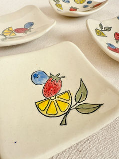 set of four colorful handmade ceramic snack plates with hand painted lemon, strawberry, blueberry decoration