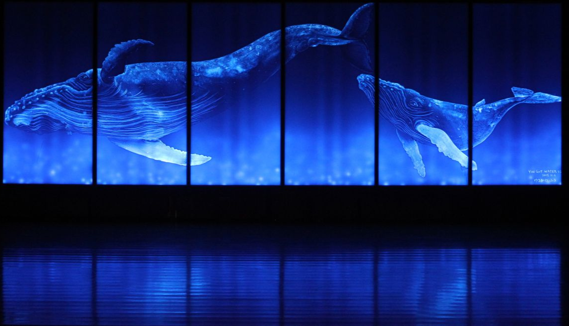 光彫り技法で描かれたクジラの親子。スタイロフォームから放たれる青い光が深海のように見える。