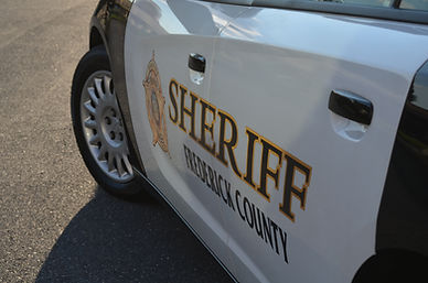 White and black patrol car door with 'SHERIFF FREDERICK COUNTY' text.