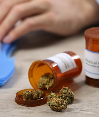 doctor-writing-on-prescription-blank-and-bottle-with-medical-cannabis-on-table-close-up.jp