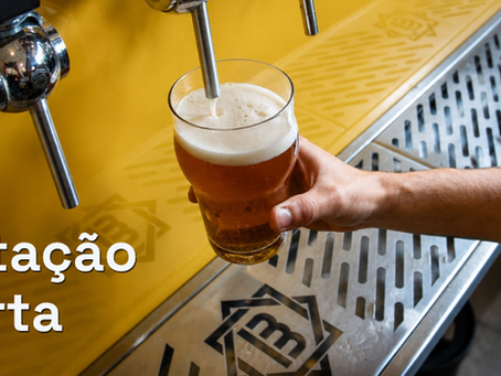 Pessoa serve chope dourado em copo numa torneira; balcão amarelo e inox; texto Captação Aberta.
