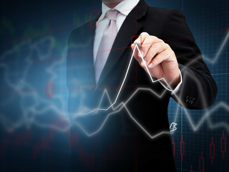 Homem de terno desenha uma linha de gráfico financeiro em fundo azul com velas vermelhas, clima corporativo e analítico.