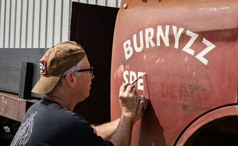 Artist hand-painting BURNYZZ SPEED on truck