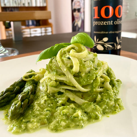 Grüner Spargel mit Pesto, Pasta, Garnelen und Parmesan angerichtet auf weißem Teller mit Olivenöl