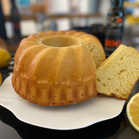 Italienischer Zitronenkuchen Ciambella al Limone auf weißem Teller mit frischen Zitronen