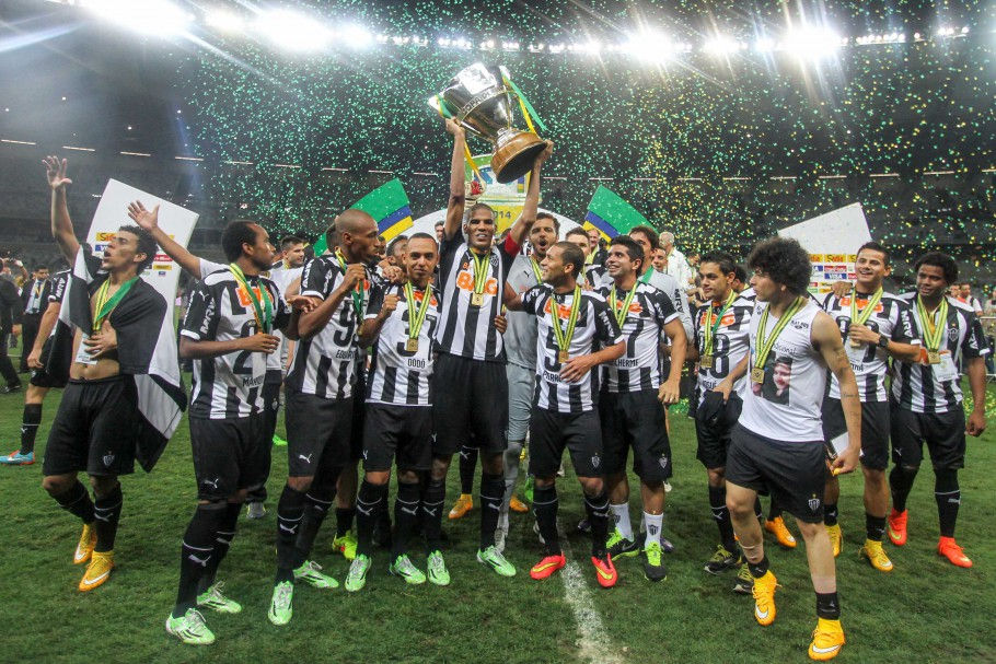 Imagem da comemoração dos jogadores do Atlético Mineiro com as medalhas e levantando a taça da Copa do Brasil 2021, ao fundo confete e a arquibancada do estádio