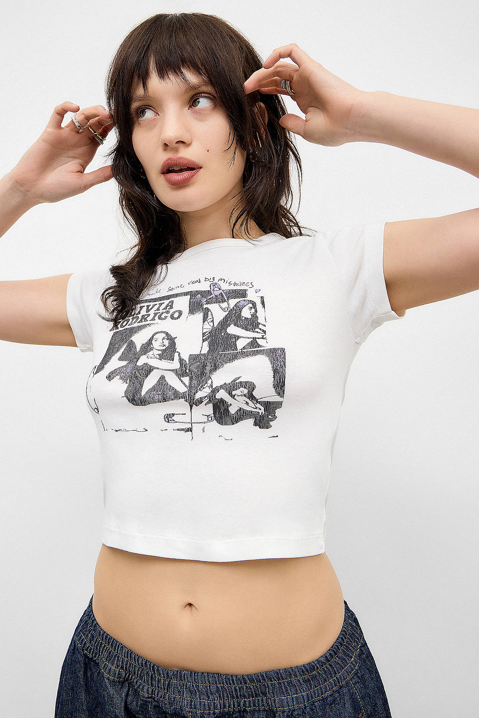 Model wearing the Urban Outfitters Olivia Rodrigo Baby T-Shirt, featuring a black-and-white graphic design inspired by the artist.
