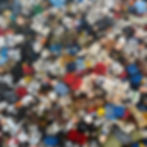 A colorful pile of assorted LEGO minifigures, some in costumes like stormtroopers, fills the frame. The background is a blue container.