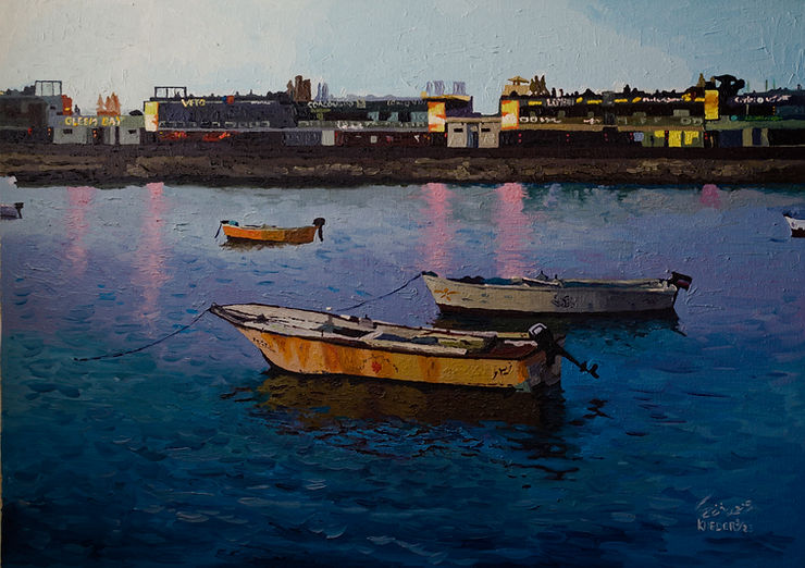 Small boats float on a calm, blue water reflecting city lights. A distant colorful skyline under a clear evening sky sets a serene mood.