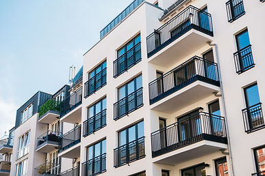 Modern white apartment building with black balconies and large windows.