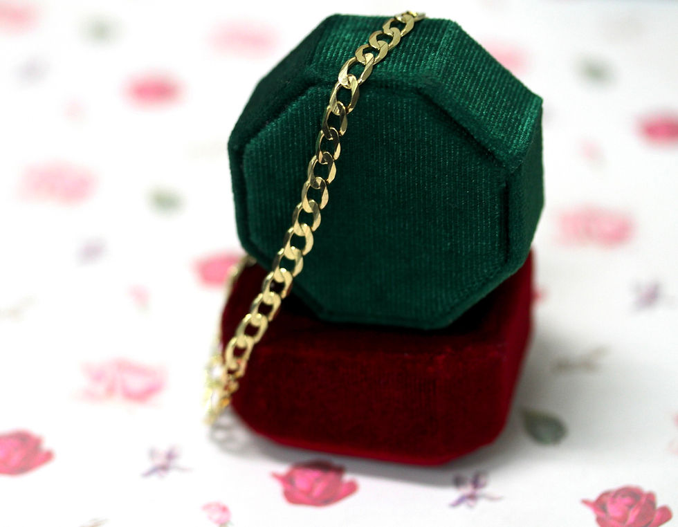 Green and red velvet jewelry boxes with a gold chain draped over. Background features a white surface with pink and green floral patterns.