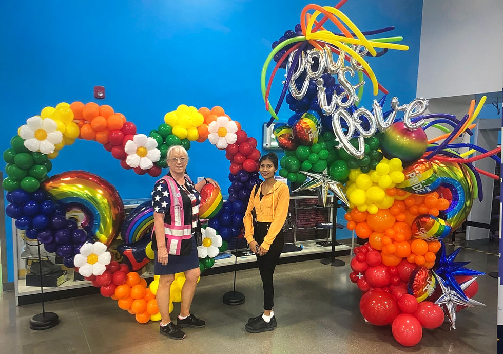 two women standing in front of a balloon display that says " love is love "
