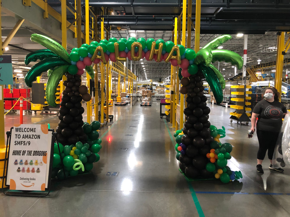a balloon archway with palm trees and the word aloha on it