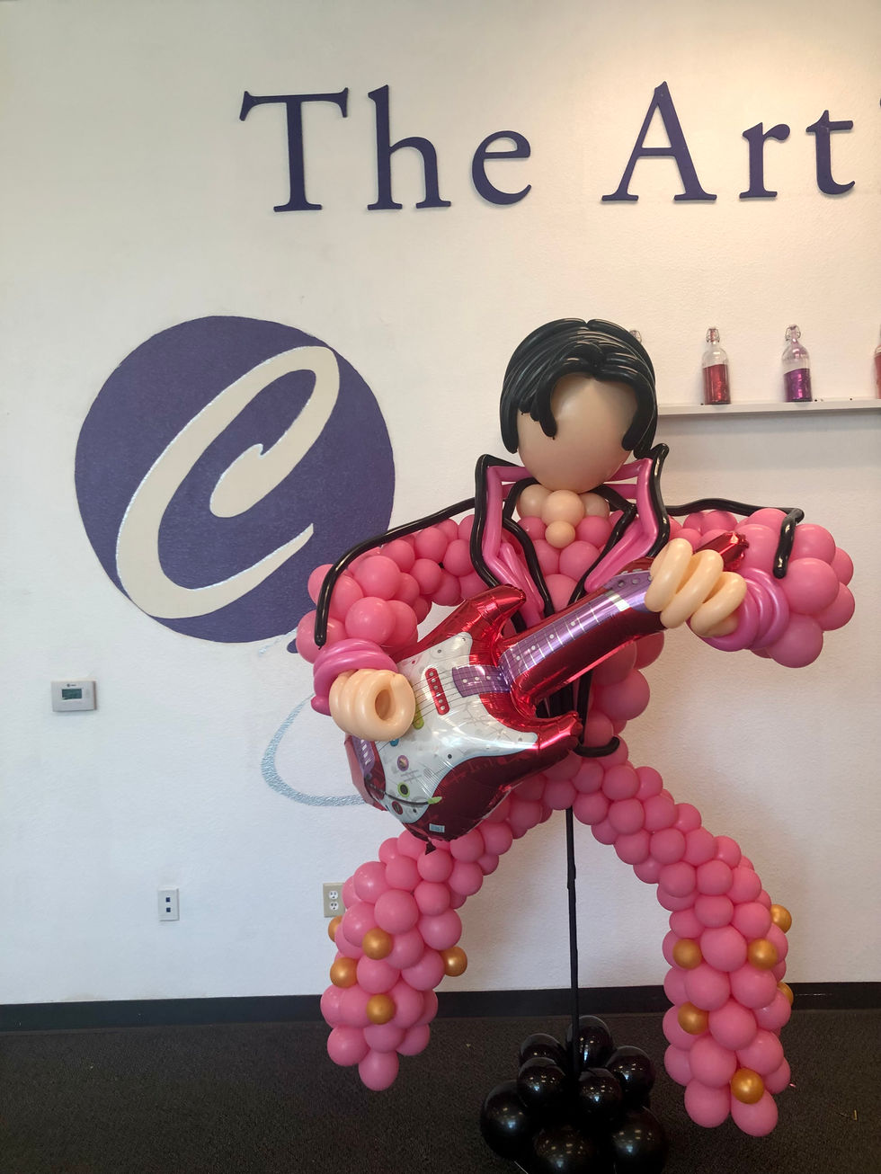 a balloon sculpture of elvis presley is in front of a sign that says the art