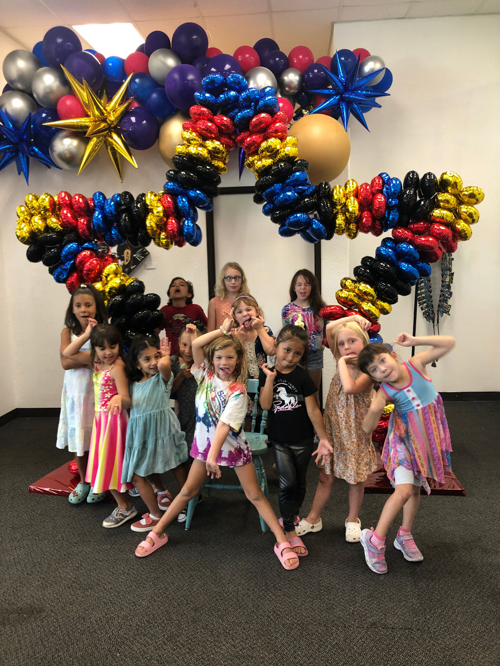a group of young girls are posing for a picture in front of balloons