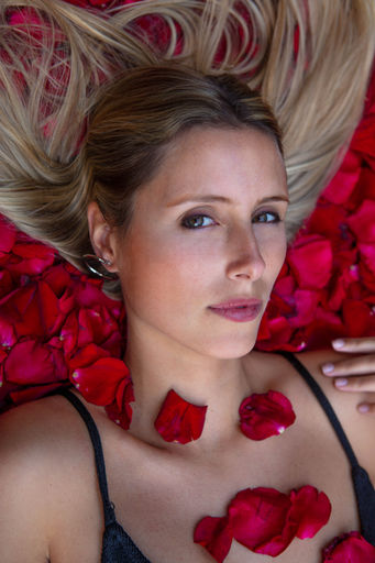 Retrato de modelo, con pétalos de rosa en exterior con luz natural.